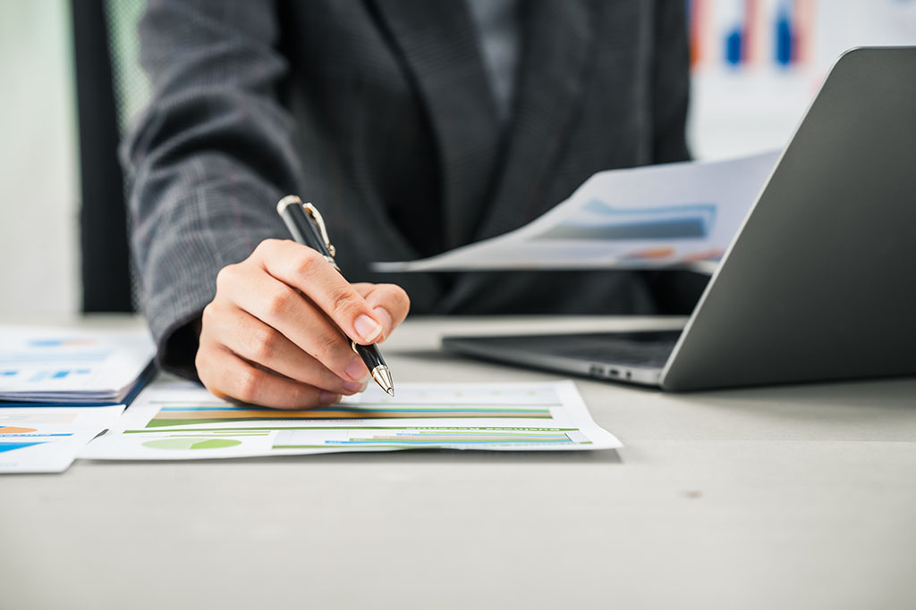 A Businesswoman Works Diligently At Her Desk, Reviewing Financia